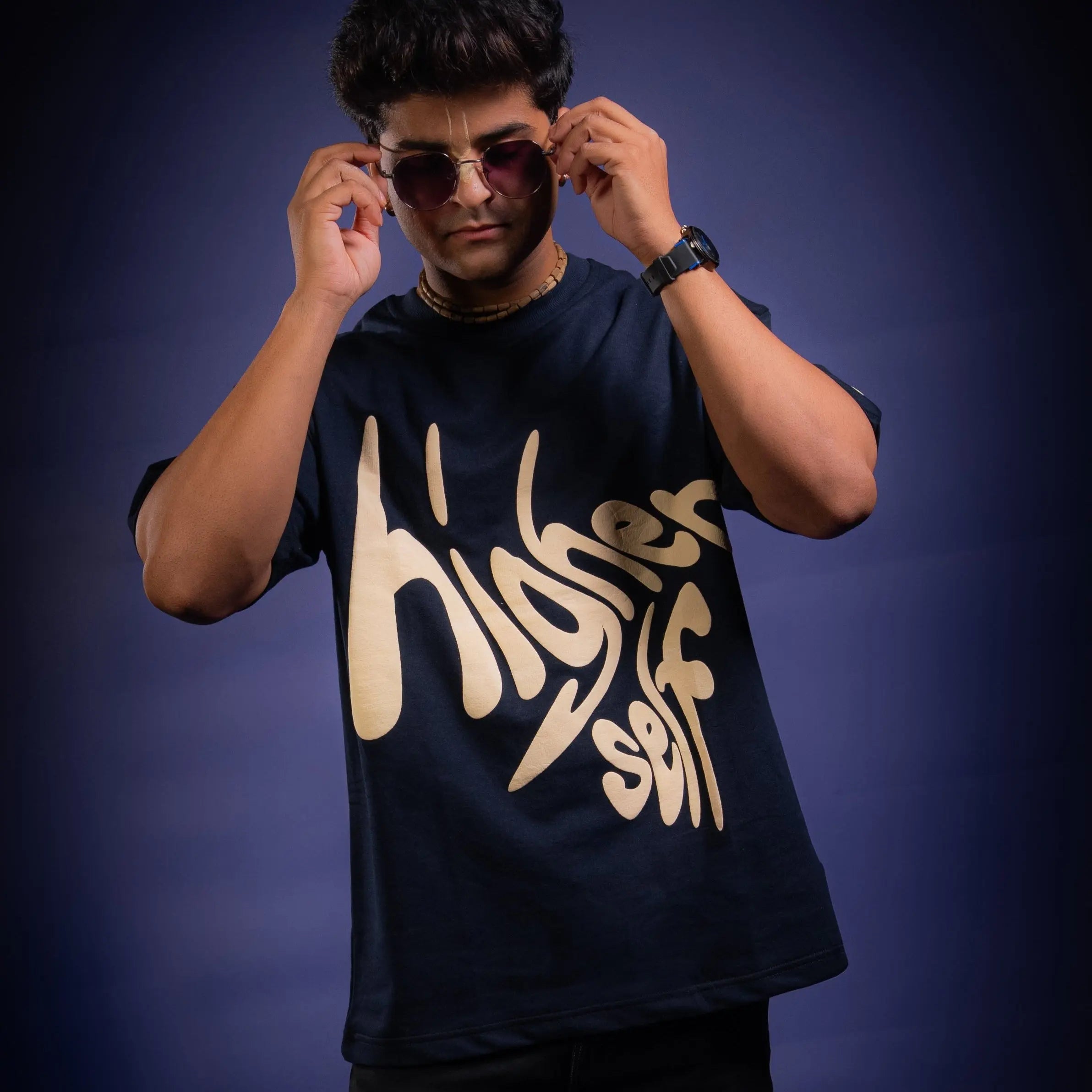 Person wearing a navy blue t-shirt with 'Higher Self' text on a dark background