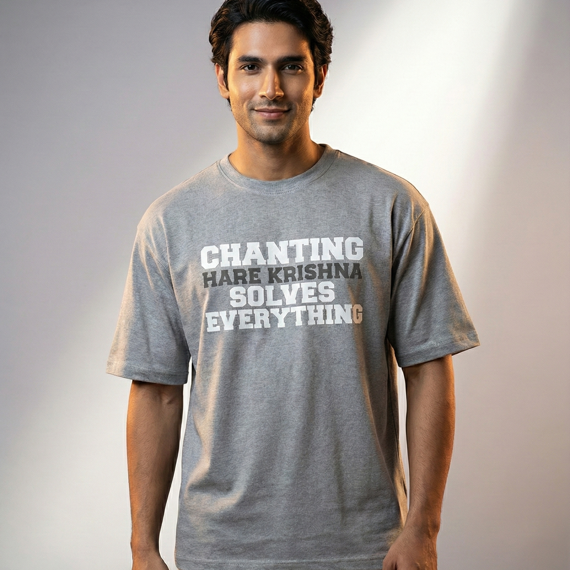 Man wearing a gray t-shirt with text standing against a plain background