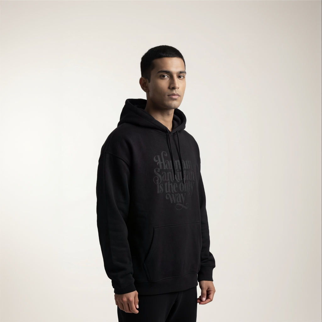 Person wearing a black hoodie with text on a plain background