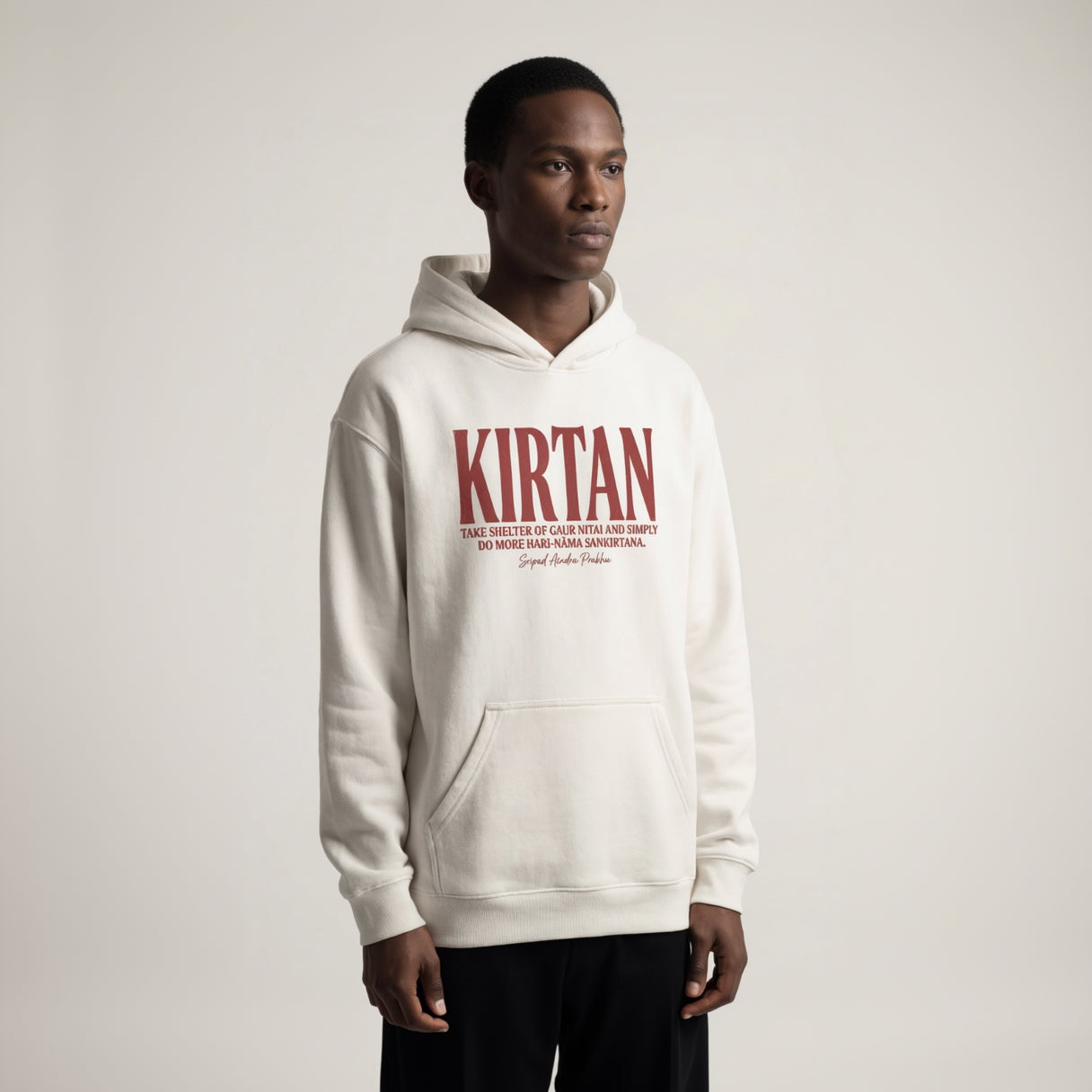 Person wearing a white hoodie with 'Kirtan' text on a plain background